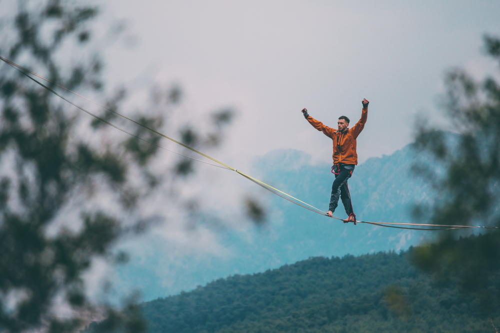 A,man,is,walking,along,a,stretched,sling.,highline,in