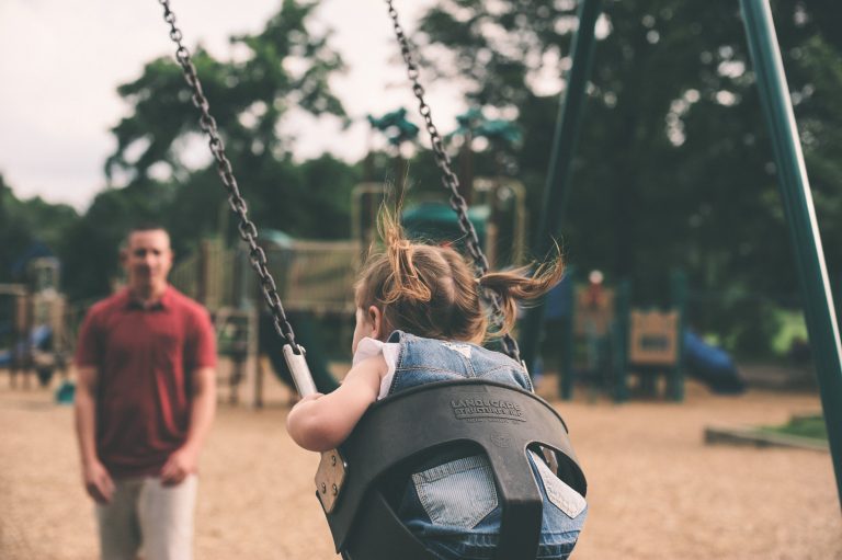A back view of a young girl swinging