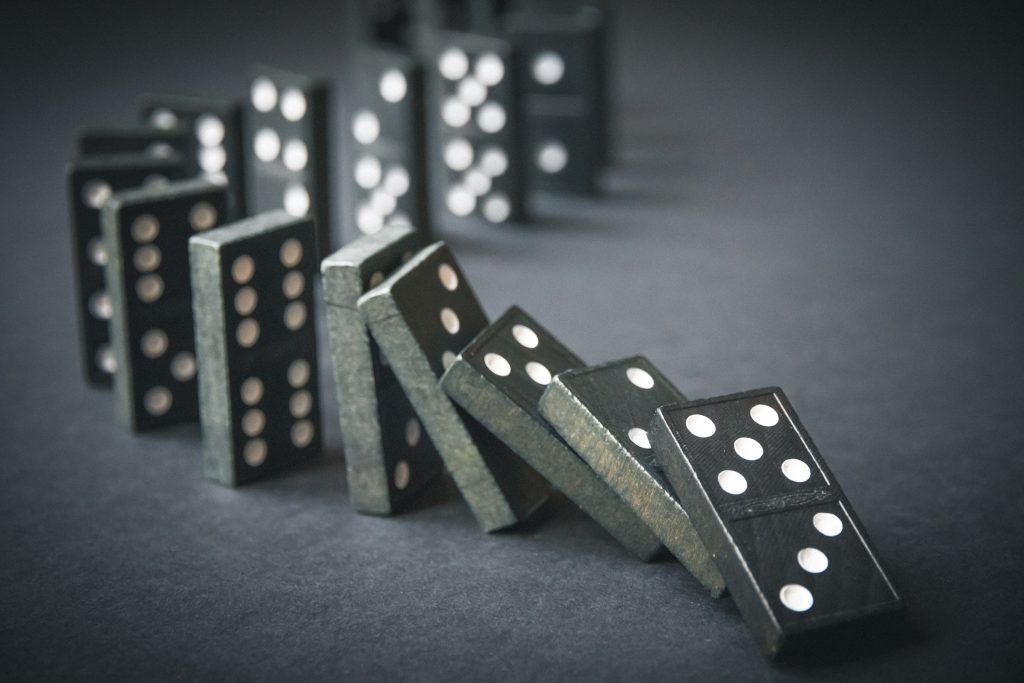 Black,Dominoes,Chain,On,A,Dark,Table,Background.,Domino,Effect