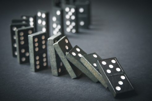 Black,Dominoes,Chain,On,A,Dark,Table,Background.,Domino,Effect
