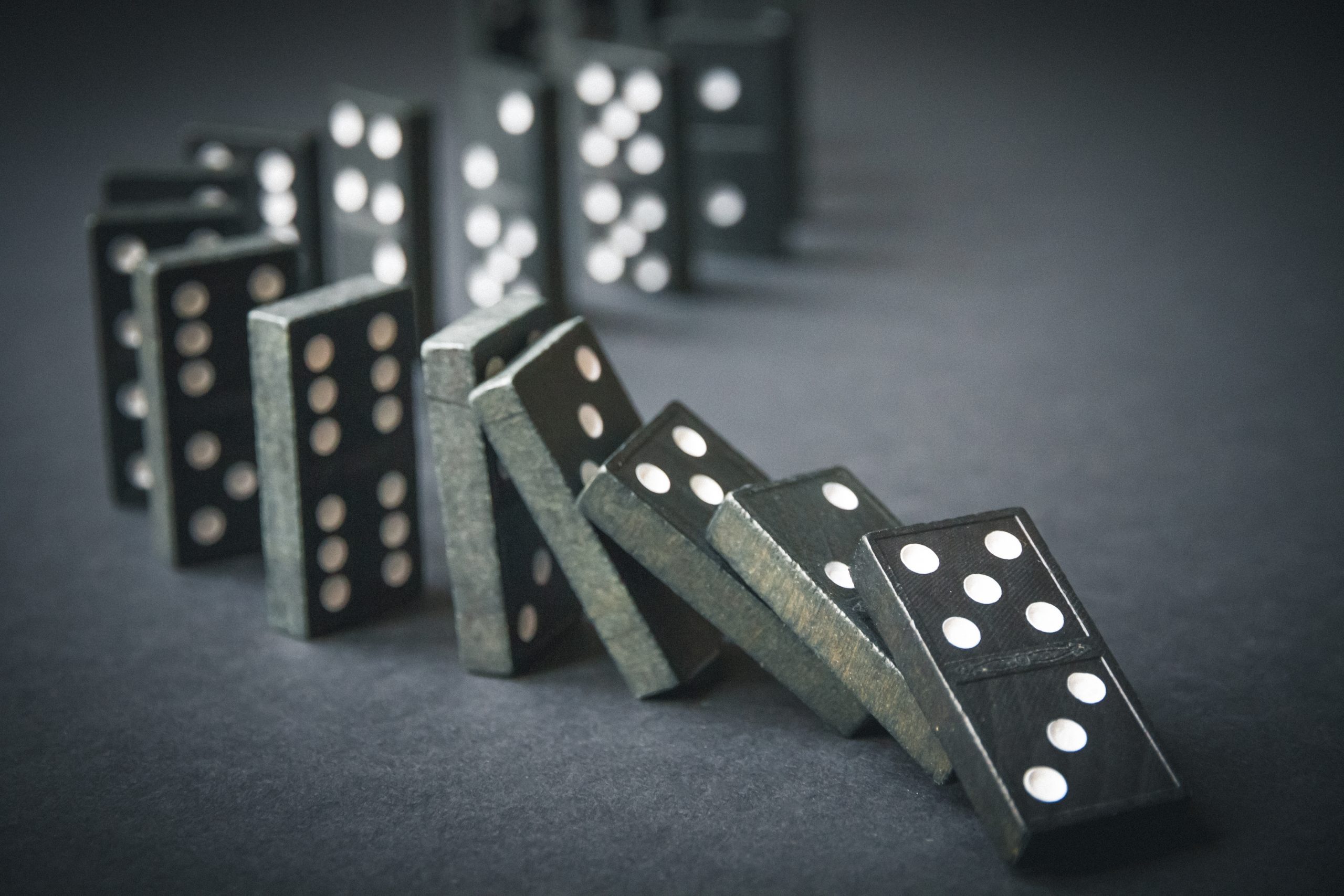 Black,Dominoes,Chain,On,A,Dark,Table,Background.,Domino,Effect